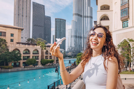 Woman joyfully holding toy plane in Dubai, symbolizing the process of securing a residence visa.